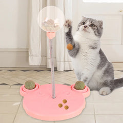 Cat playing with a pink interactive pet toy on a tiled floor.