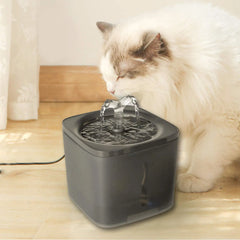 Cat drinking from a pet water fountain on a wooden floor.